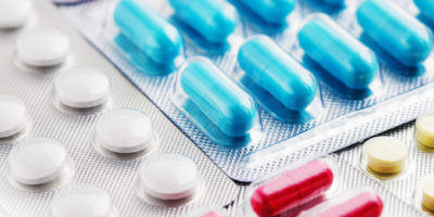 Haufen von medizinischen Pillen in Weiß, Blau und anderen Farben. Pillen in Plastikverpackung. Konzept der Gesundheitsversorgung und Medizin.