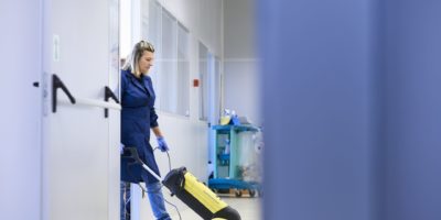 Frauenarbeit, professionelles Dienstmädchen, das Boden mit Maschinen im Industriegebäude reinigt und wäscht. Kopierraum in voller Länge