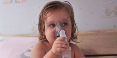 Weibliches Kind mit Inhalator allein.