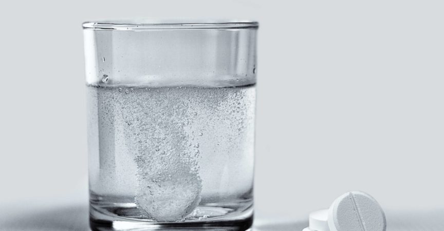 Nahaufnahme von Brausetabletten, die sich in einem Glas Wasser auflösen