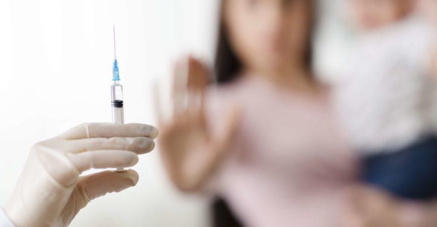 Stoppen Sie die Impfung von Kindern. Mutter hält Baby und lehnt Arzt mit Spritze ab, selektiver Fokus
