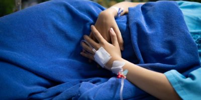 Patientin, die unter Bauchschmerzen leidet, während sie auf Krankenhausbett liegt.