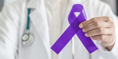 Symbolische Bogenfarbe des violetten violetten Bandes auf der Handunterstützung des Arztes für Hodgkin-Lymphom und Hodenkrebsbewusstsein