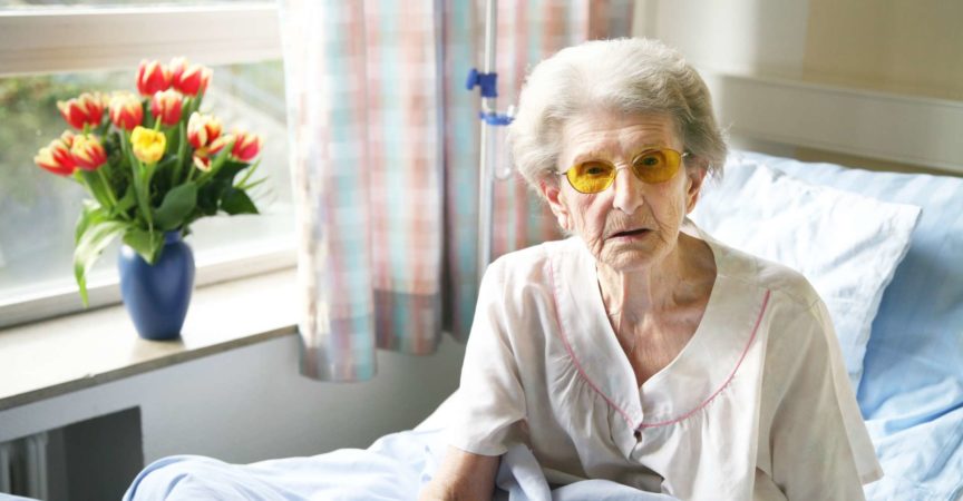 Alte Frau im Spital sitzt im Bett