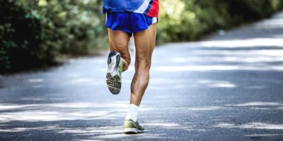 Tscheljabinsk, Russland - 9. Juli 2016: Füße alter männlicher Athlet läuft auf der Straße im Wald während des Sommerhalbmarathons