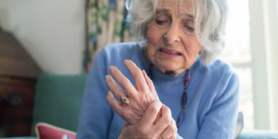 Ältere Frau zu Hause, die mit Arthritis leidet
