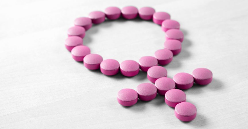 Weibliche Gesundheit. Geschlechtssymbol aus rosaroten Pillen oder Tabletten auf Holztisch