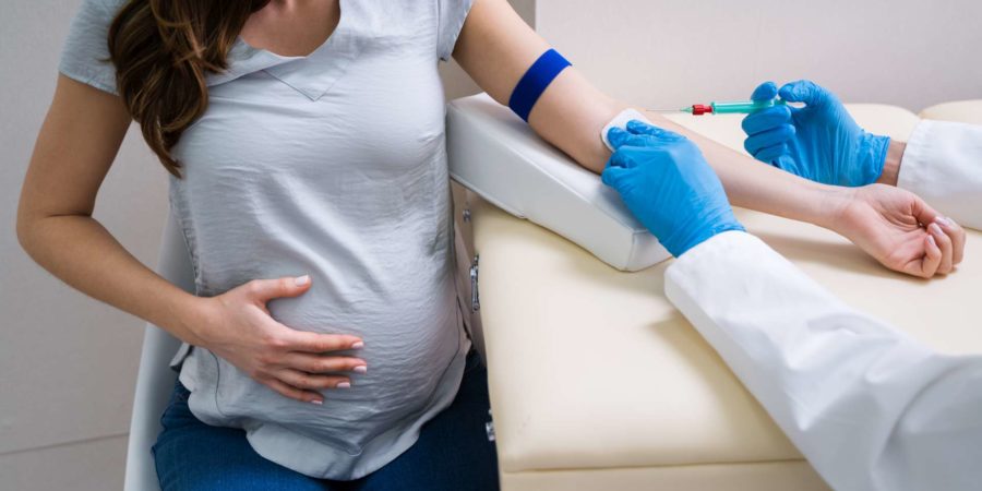 Nahaufnahme des Arztes, der schwangere Patientin mit Spritze injiziert, um Blutprobe zu sammeln