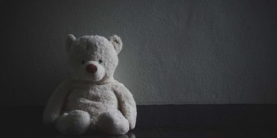 Einsamer Teddybär, der im dunklen Raum sitzt (Konzept über die Liebe)