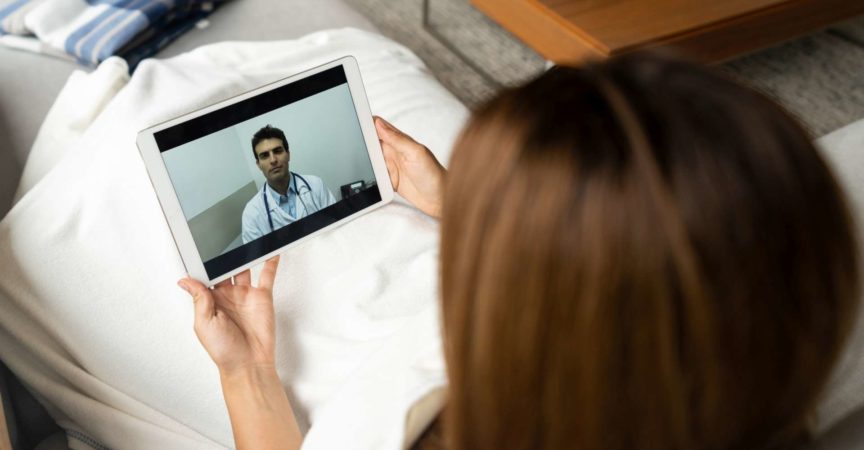Kranke Frau in Quarantäne im Gespräch mit ihrem Arzt online über einen Tablet-Computer - Gesundheitskonzepte
