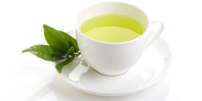 Japanischer grüner Tee und frische grüne Teeblätter auf weißem Hintergrund