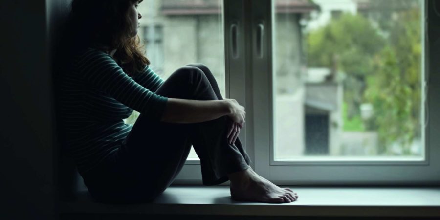 Traurige junge Frau, die am Fenster sitzt