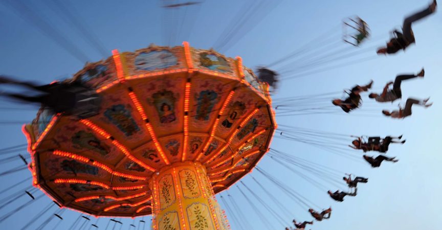 Menschen auf einer Kettenschaukel fahren in einem Vergnügungspark.