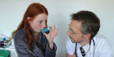 Krankenhausarzt zeigt junges Mädchen, wie man Salbutamol-Inhalator verwendet