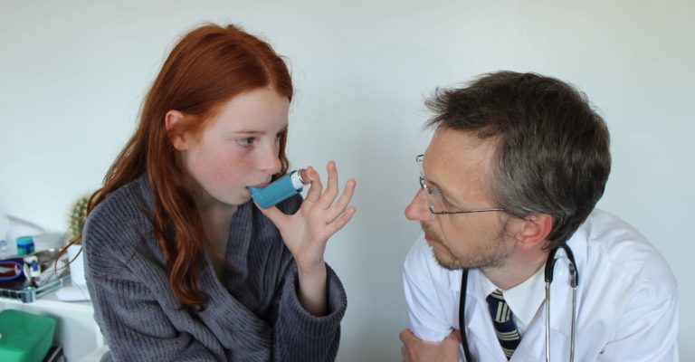 Krankenhausarzt zeigt junges Mädchen, wie man Salbutamol-Inhalator verwendet