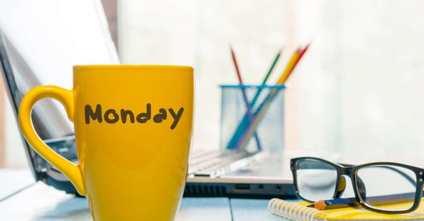 Montag geschrieben auf gelbe Kaffee- oder Teetasse am hölzernen Brettertisch, am Arbeitsplatz, im Bürosonnenlichtmorgenhintergrund.
