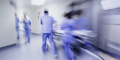 Ärzte und Krankenschwestern ziehen Krankenhauswagen,