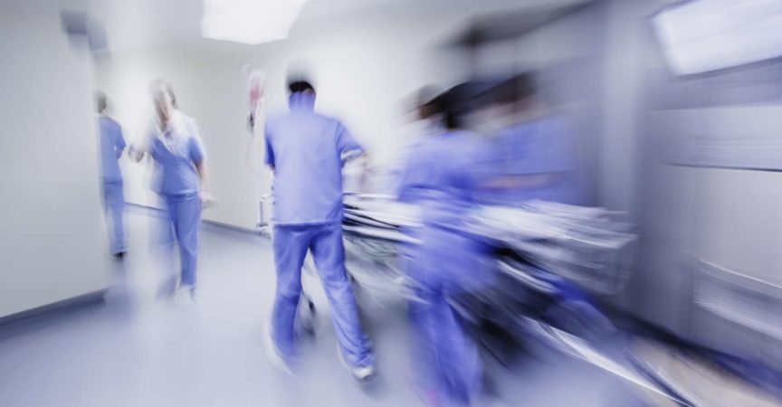 Ärzte und Krankenschwestern ziehen Krankenhauswagen,