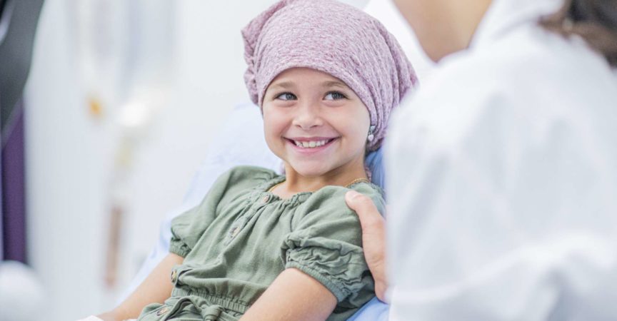 Ein kleines Mädchen lächelt mit ihrer Ärztin an ihrem Bett