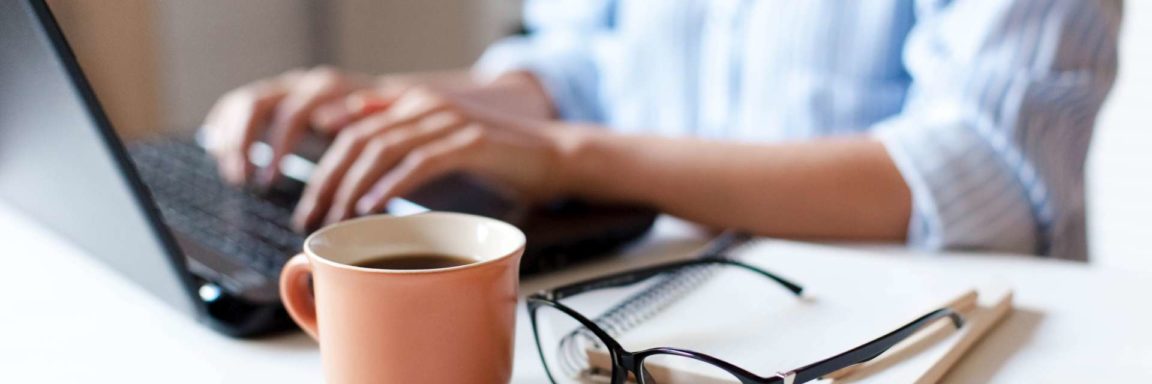 Fernarbeit von zu Hause aus. Freiberuflicher Arbeitsplatz in der Küche mit Laptop, Tasse Kaffee