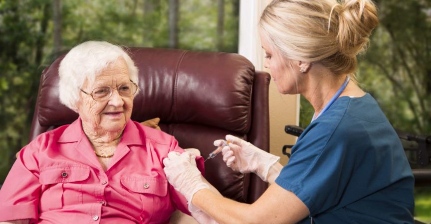 Krankenschwester im häuslichen Gesundheitswesen, die einer älteren Frau eine Injektion gibt.