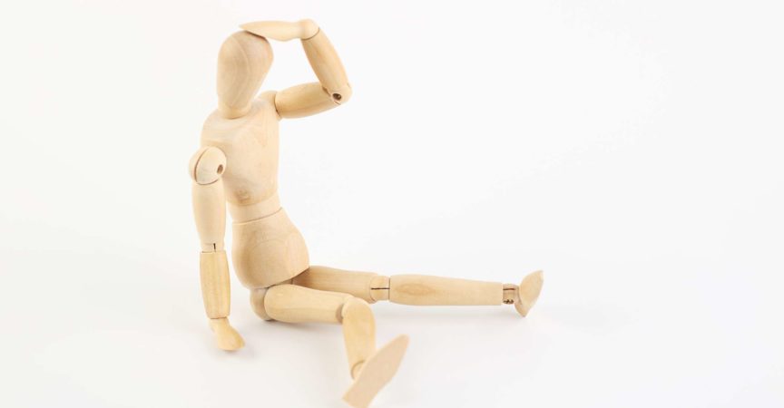 Depressive oder erschöpfte Holzpuppe sitzt auf dem Boden