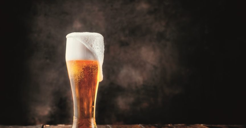 Glas frisches und kaltes Bier auf dunklem Hintergrund. Speicherplatz kopieren.