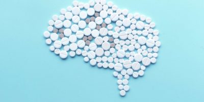 Gehirn Darstellung aus Tabletten und Pillen vor türkisem Hintergrund