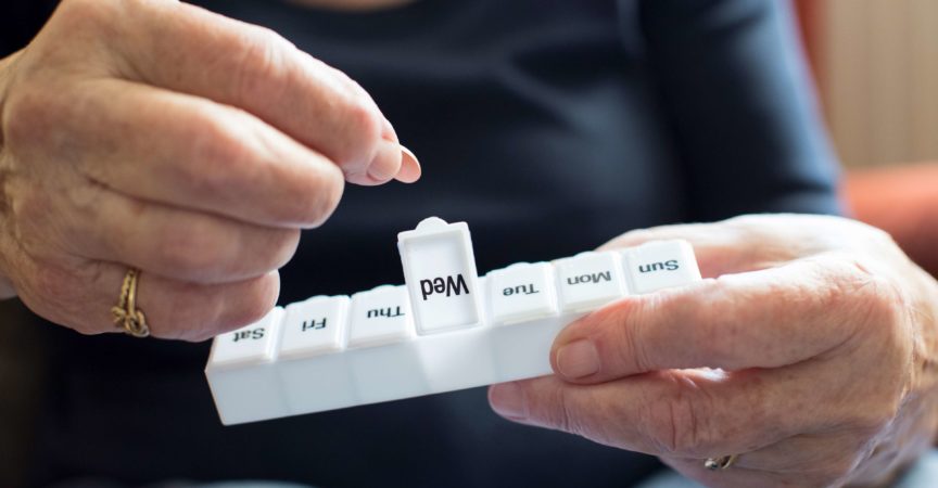 Ältere Frau, die Medikamente aus der Pillendose nimmt
