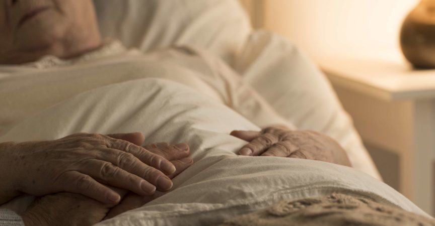 Nahaufnahme der Hand des Senioren auf der Hand der sterbenden älteren Person als Zeichen der Unterstützung während der Krankheit