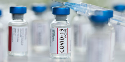 Covid-19 Coronavirus-Impfstoffflaschen mit Spritzenmakro-Nahaufnahme, flachem Fokus
