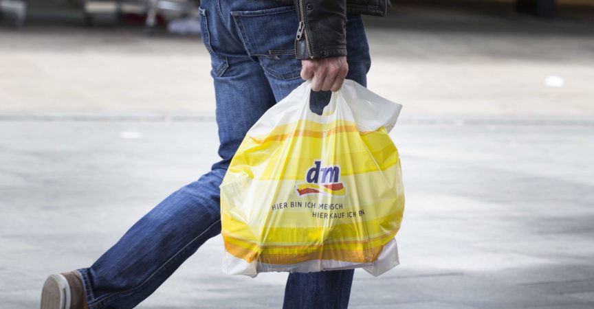 Ein unkenntlicher Fußgänger mit einer Plastiktüte vom dm-Drogeriemarkt im Vorbeigehen in einer Einkaufsstraße in der Wiesbadener Innenstadt. dm-drogerie-markt ist eine Drogeriemarktkette für Kosmetik, Gesundheits- und Haushaltsprodukte sowie Lebensmittel.