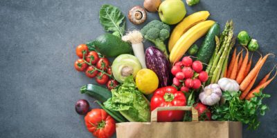 Gesunde Auswahl an Lebensmitteln. Einkaufstasche voller frischem Gemüse und Obst. Flach lag Essen auf dem Tisch
