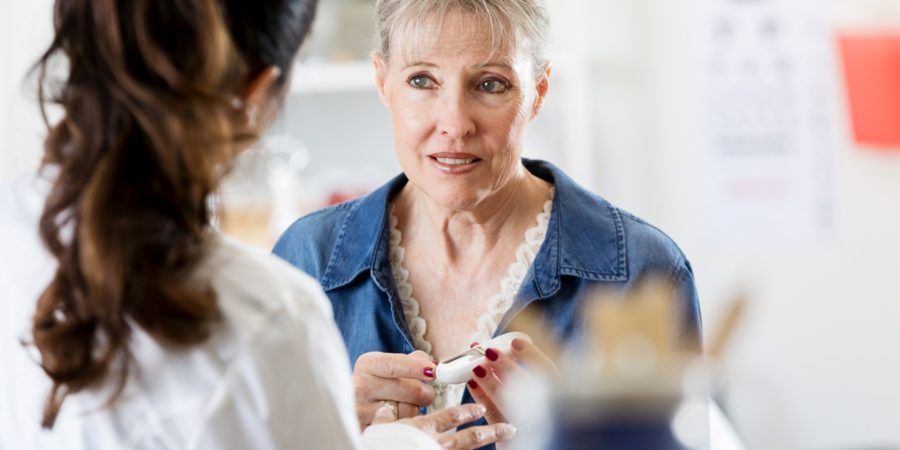 Eine betroffene ältere Frau hält ein Glaukometer in der Hand, als sie mit einer Ärztin über ihre Diabetesdiagnose spricht.