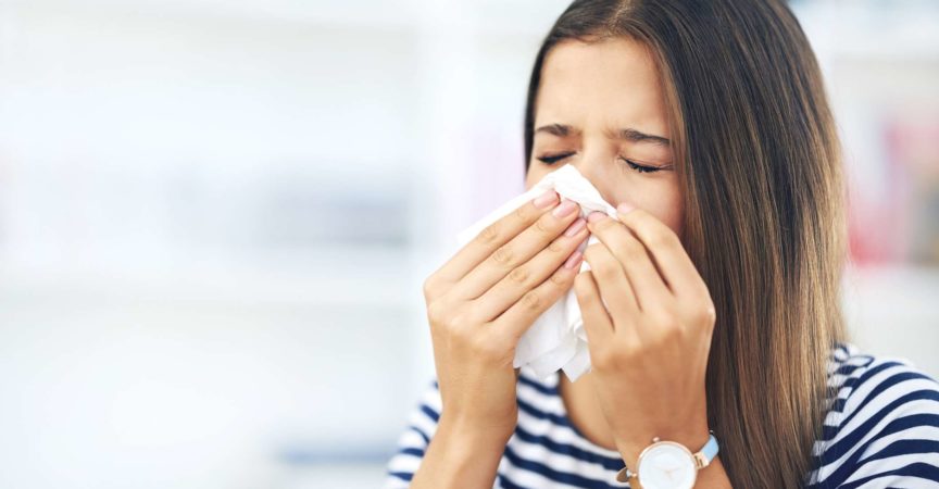 Aufnahme einer jungen Frau mit Allergien, die zu Hause in ein Taschentuch niest