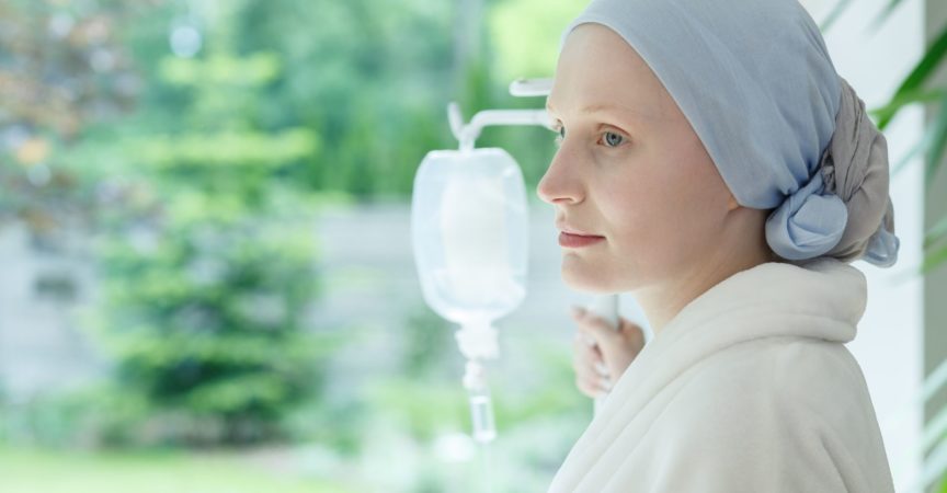 Junge Frau mit Hautkrebs, die auf einem Tropfen im Krankenhaus steht