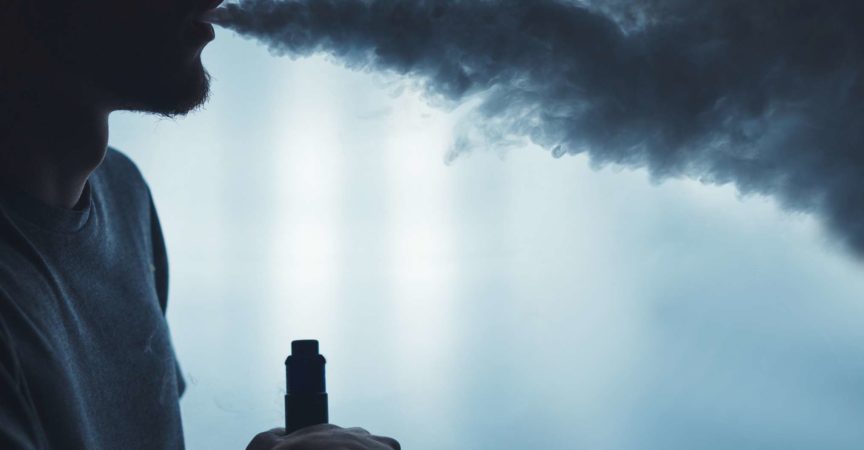 Ein bärtiger Mann in den Dampfwolken von der Nahaufnahme der elektronischen Zigarette. vaping Mann