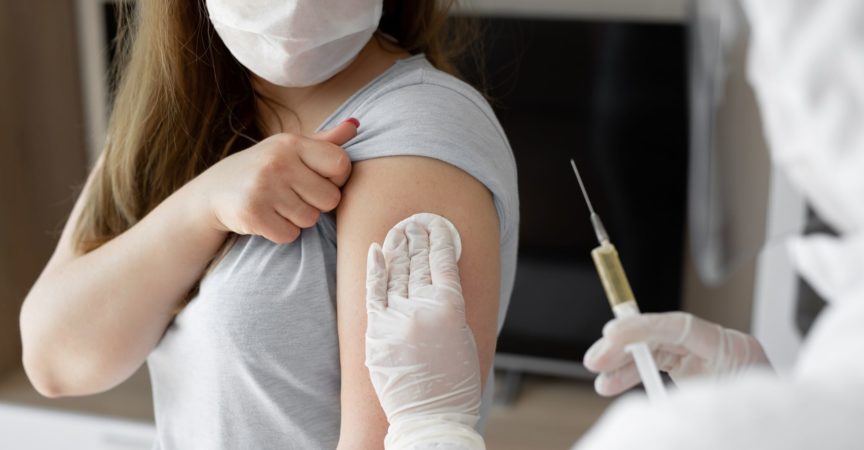 Arzt in persönlichem Schutzanzug oder PSA injiziert Impfstoff, um die Immunität einer Patientin zu stimulieren, bei der das Risiko einer Coronavirus-Infektion besteht. Coronavirus, Covid-19 und Impfkonzept