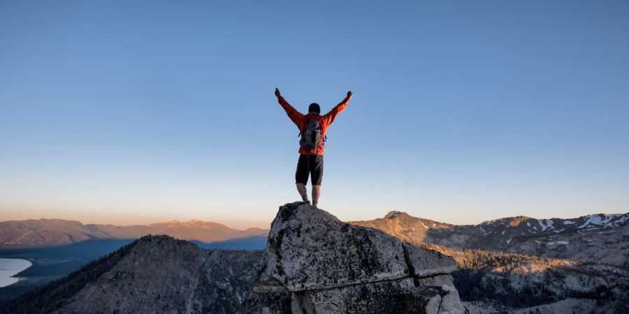 Ein Kletterer erreicht den Gipfel eines exponierten Berggipfels im Hinterland von Tahoe, Kalifornien