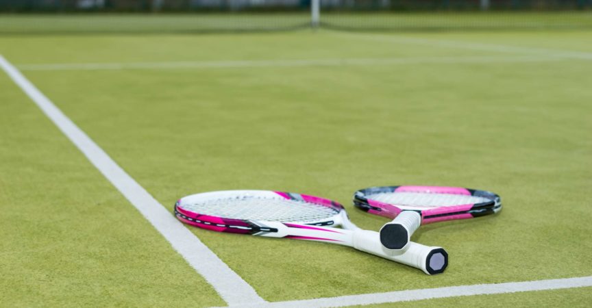 Rosa Tennisschläger, der draußen auf dem Rasenplatz liegt