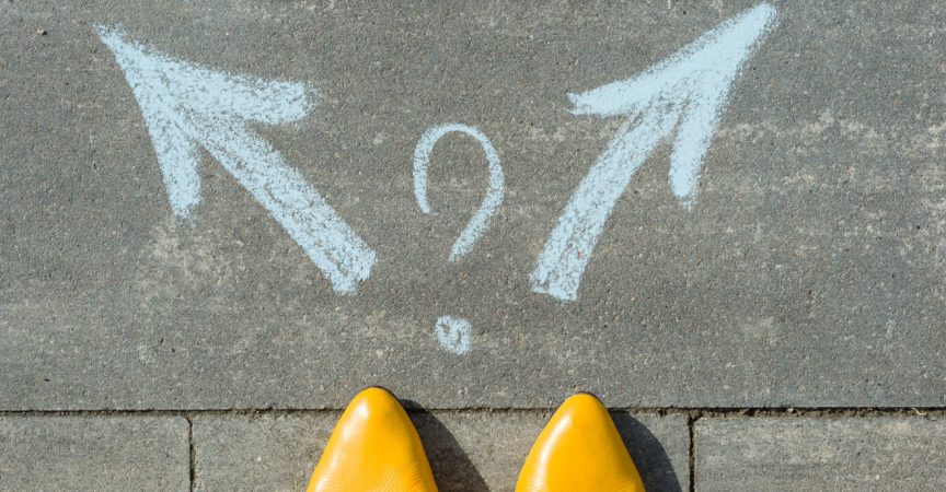 Weibliche Beine mit 2 Pfeilen und Fragezeichen, auf den Asphalt gemalt.