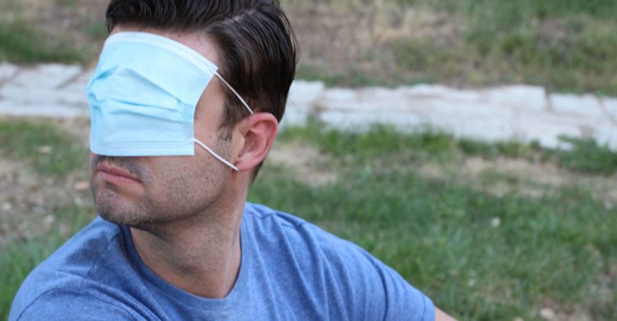 Mann, der seine Vision mit chirurgischer Maske bedeckt.