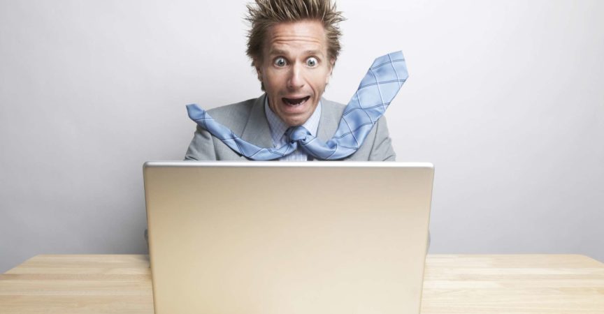 Überraschter Geschäftsmann Büroangestellter sitzt an seinem Schreibtisch und schaut auf seinen Computerbildschirm