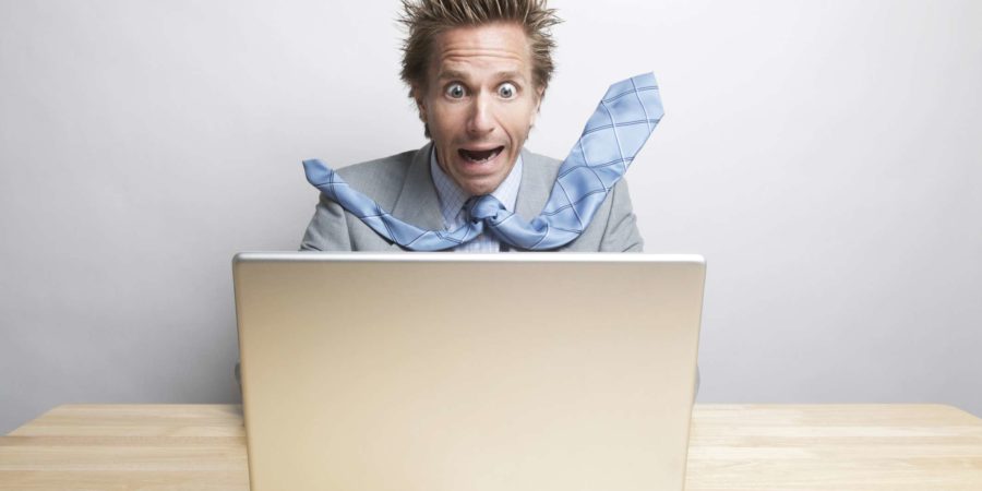 Überraschter Geschäftsmann Büroangestellter sitzt an seinem Schreibtisch und schaut auf seinen Computerbildschirm