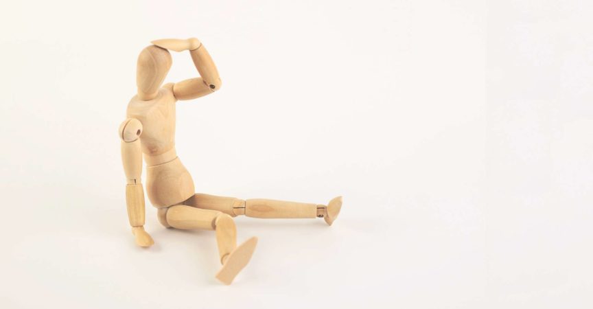 Depressive oder erschöpfte Schaufensterpuppe aus Holz, die unten sitzt