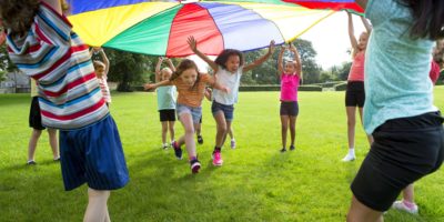 Kinder spielen mit einem bunten Fallschirm