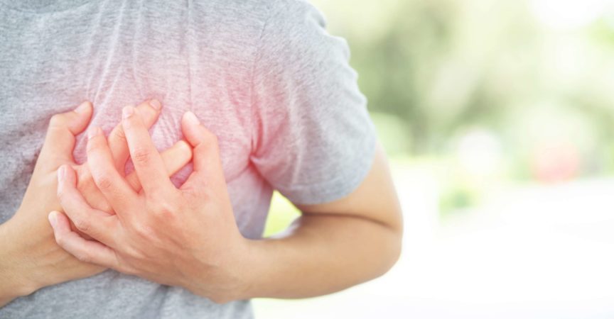 Beide Hände umfassen die linke Brust einer Person mit Brustschmerzen.