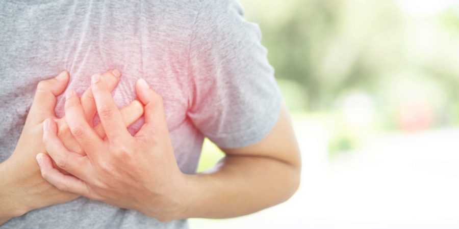 Beide Hände umfassen die linke Brust einer Person mit Brustschmerzen.