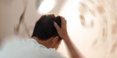 Konzept der Schwindelkrankheit. Mann Hände auf den Kopf fallen Kopfschmerzen Schwindelgefühl Drehschwindel, ein Problem mit dem Innenohr, dem Gehirn oder der sensorischen Nervenbahn.