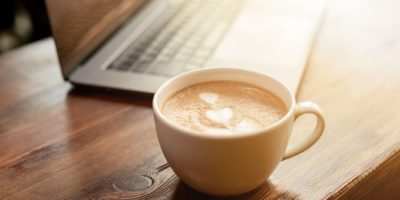 Tasse Kaffee-Cappuccino mit grauem Laptop auf Holztisch. Geschäftskonzept